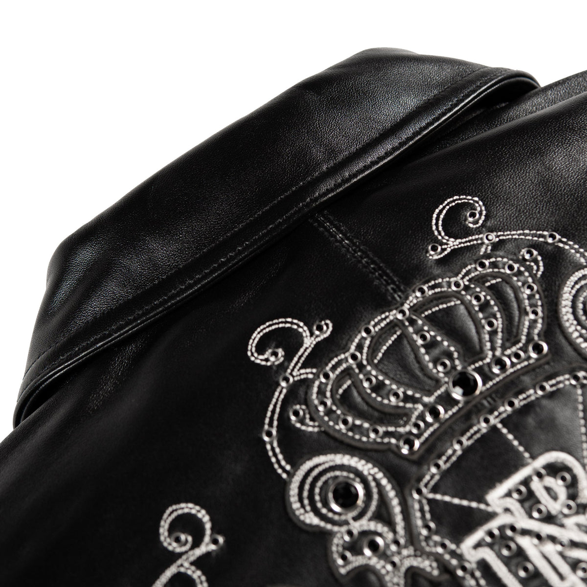 Close-up of a black leather jacket featuring detailed silver rhinestone embroidery of a crown and decorative lettering on the shoulder.