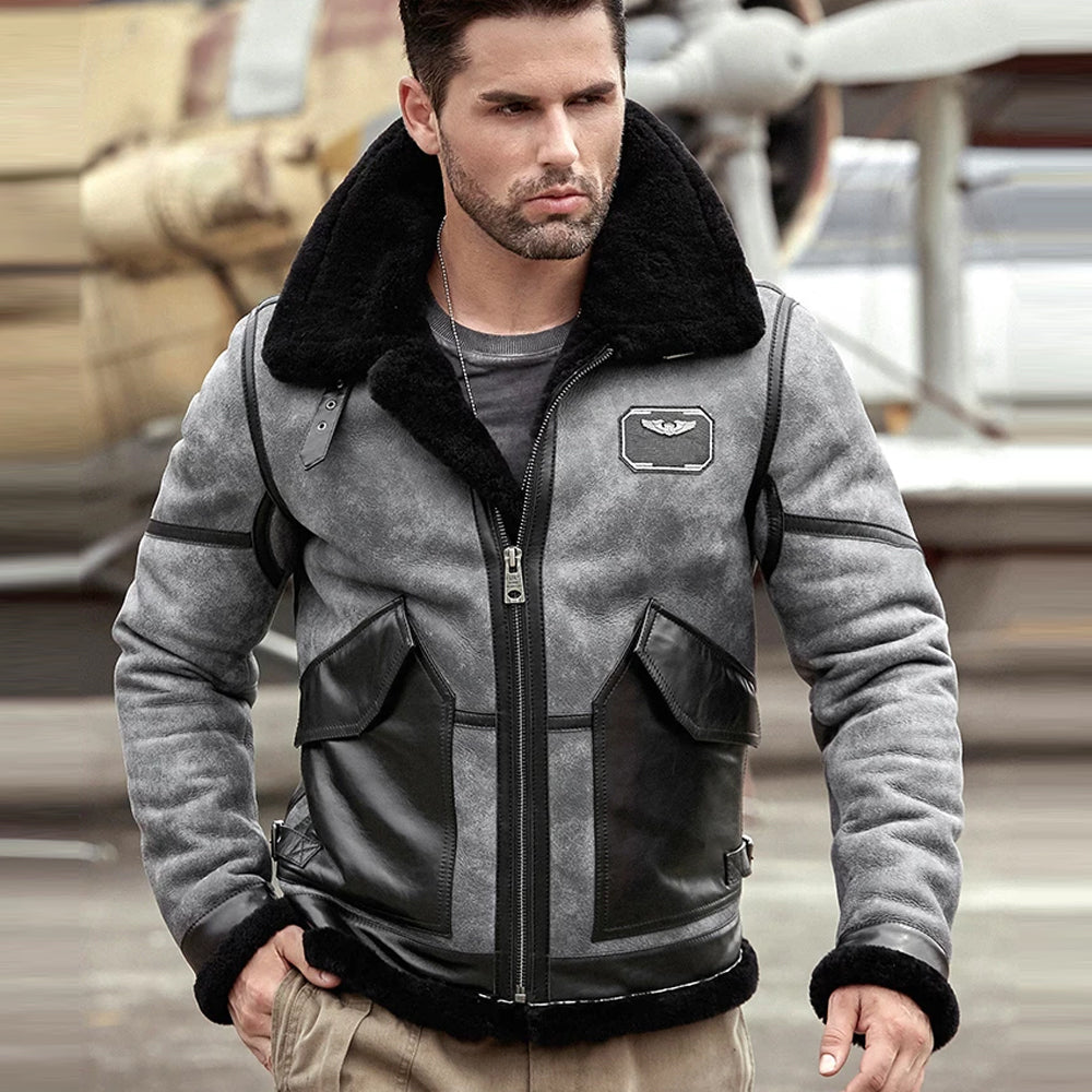 Man wearing a gray and black jacket with leather accents in an outdoor setting.