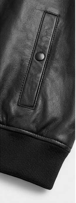 Close-up of a black leather jacket sleeve showing a vertical welt pocket with a snap button closure and a ribbed knit cuff.