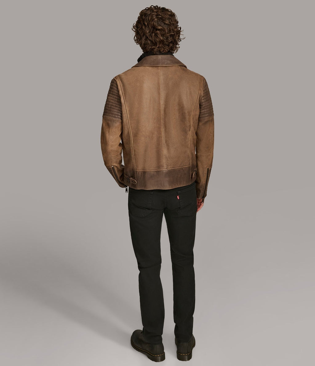 Person wearing a brown leather jacket on a plain background