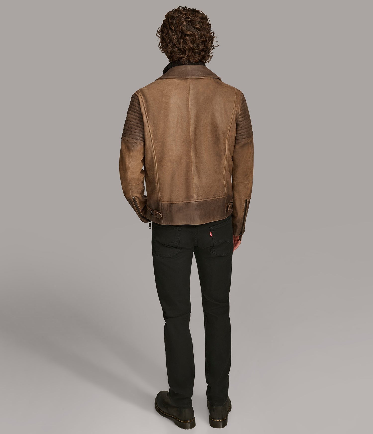Person wearing a brown leather jacket on a plain background