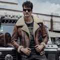 Man wearing a brown leather jacket with fur lining, sunglasses, and a black t-shirt with graphics, standing in front of a vehicle.