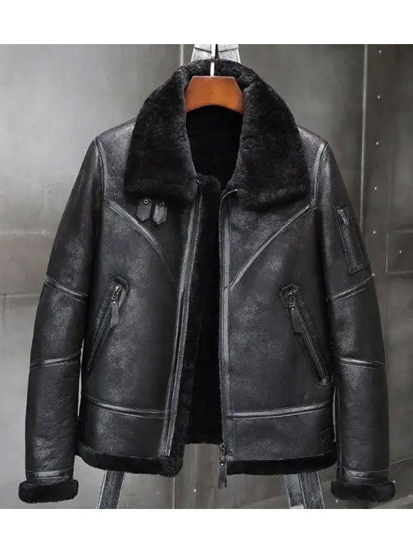 A black faux-leather aviator-style jacket with a thick black shearling-style collar, displayed on a hanger against a dark gray textured wall.