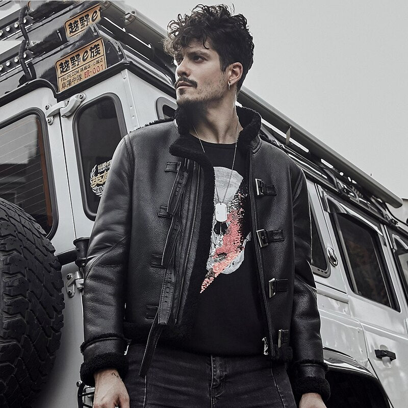 Man standing in front of a vehicle wearing a black jacket and graphic t-shirt.