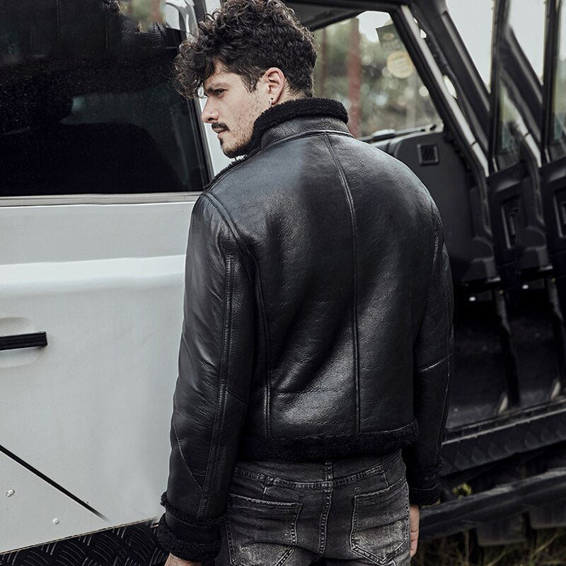 Man wearing a black leather jacket standing next to an open vehicle door.