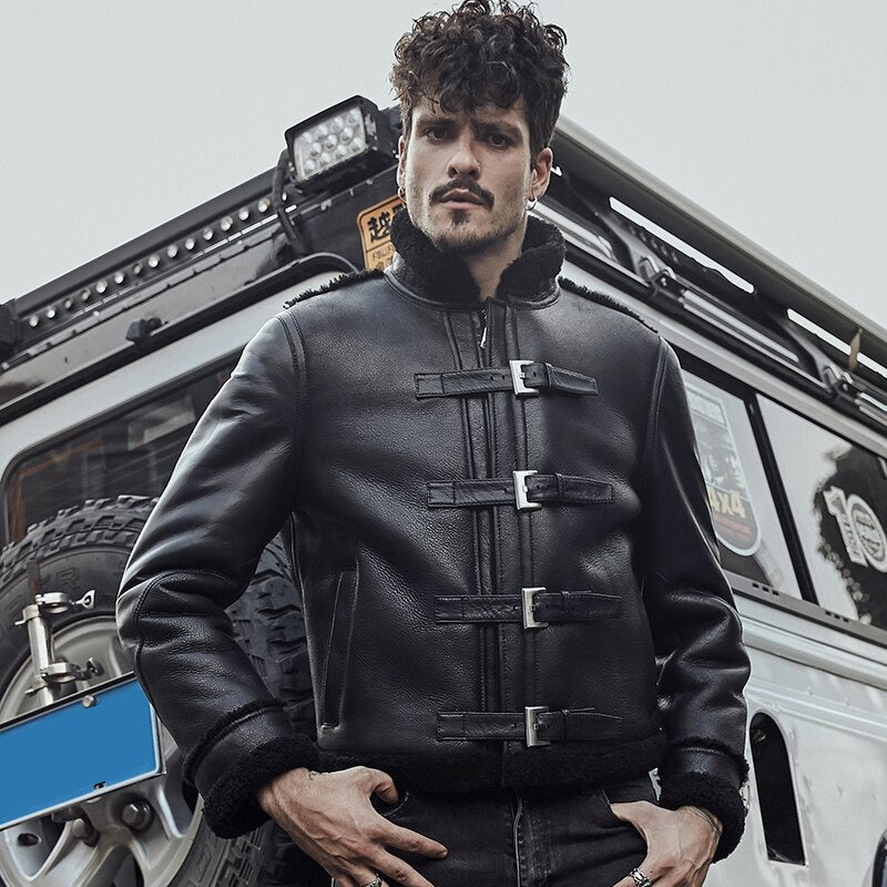 Man wearing a black leather jacket standing in front of a white Jeep with off-road equipment.
