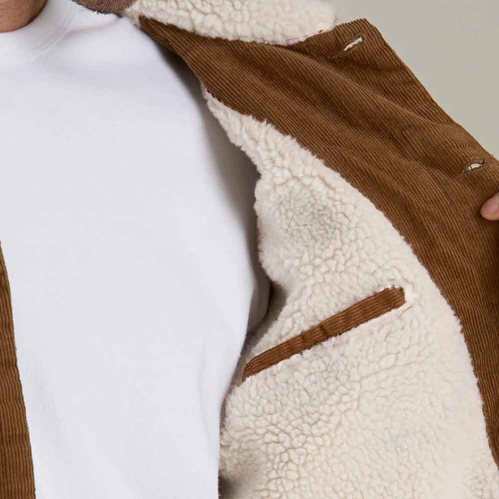 Close-up of a brown corduroy jacket with a thick cream sherpa lining, worn over a white shirt.