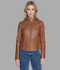 Woman wearing a brown leather jacket with a geometric pattern on a gray background