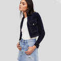 Woman wearing a navy jacket with studded details on a light gray background
