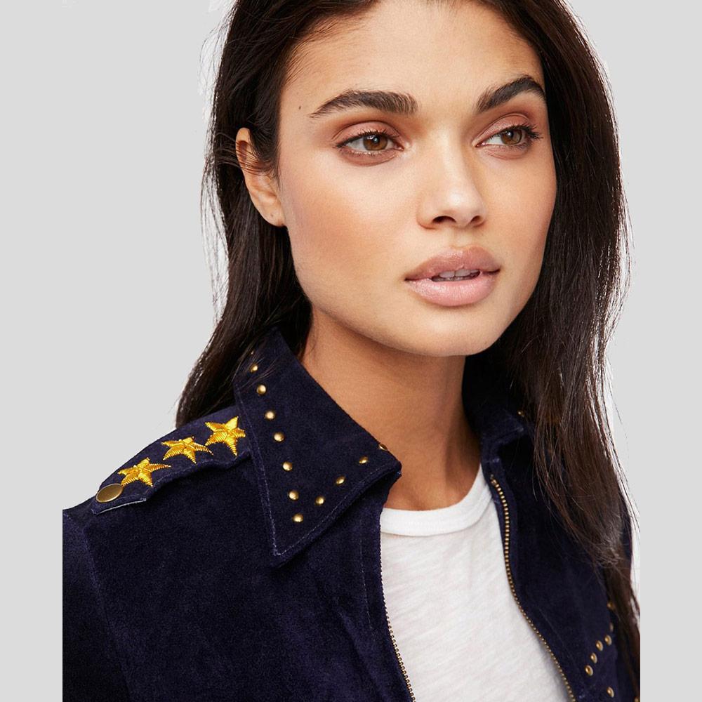 Woman wearing a navy jacket with gold star details on a gray background