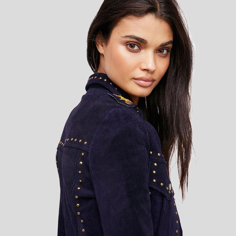 Woman wearing a navy blue jacket with gold buttons on a gray background