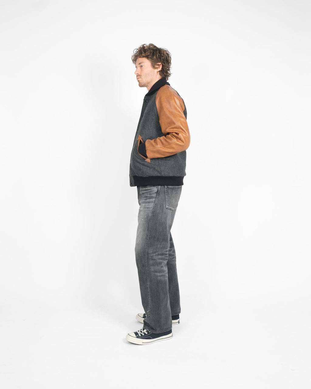 Person wearing a two-tone jacket and jeans standing against a white background