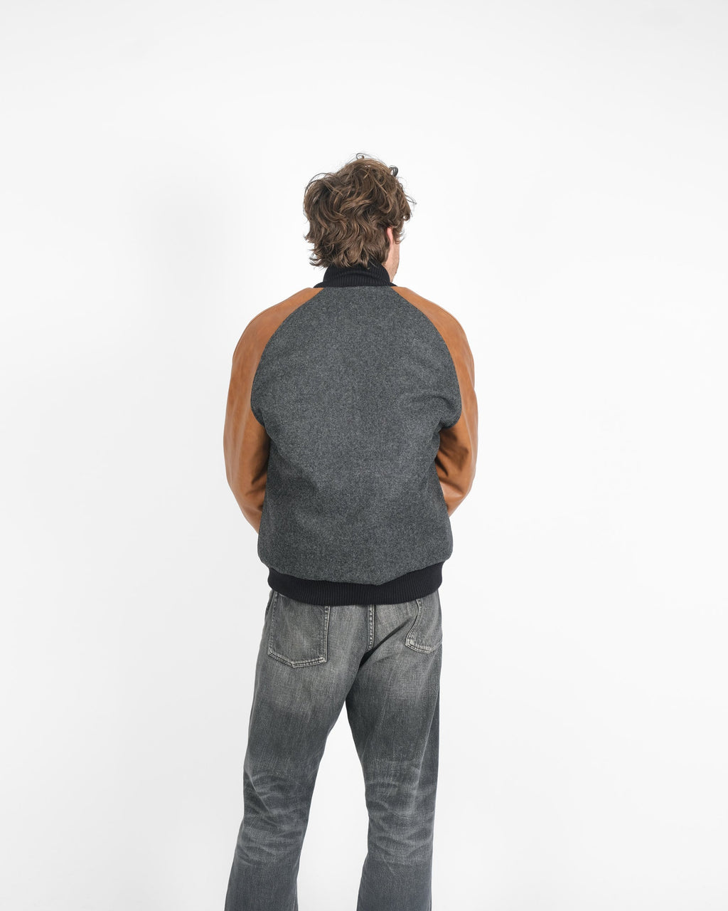 Person wearing a gray and brown jacket with a white background