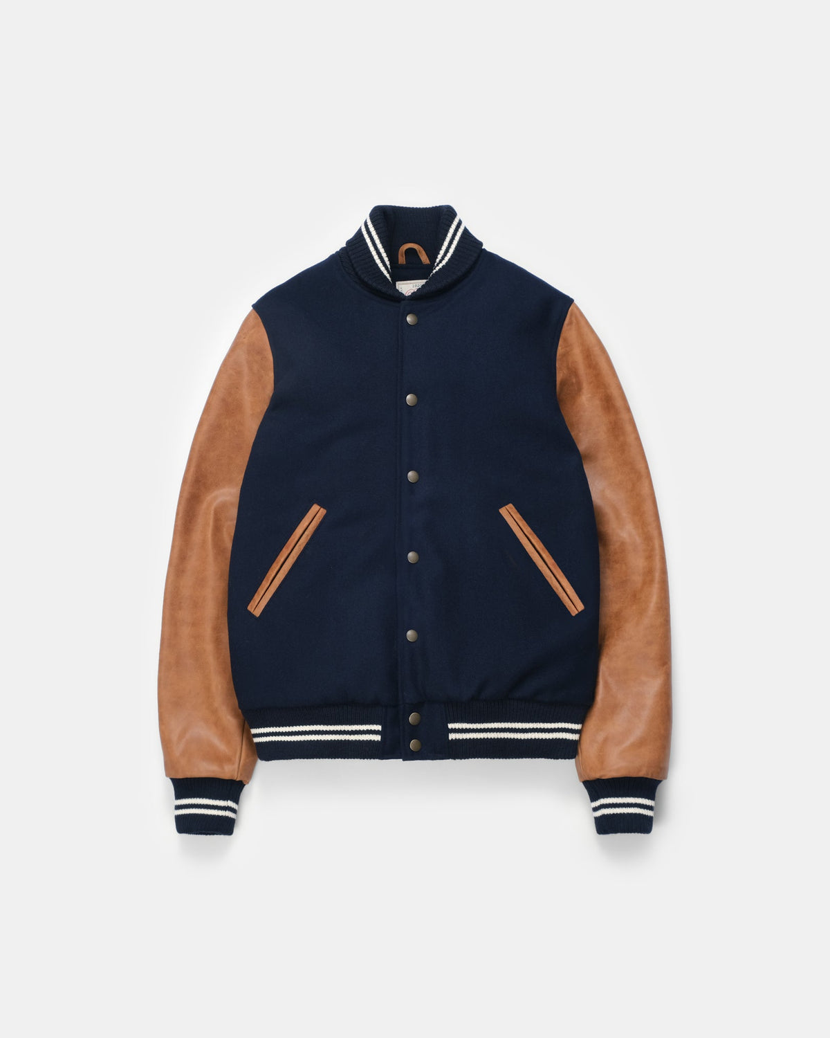 Navy varsity jacket with brown leather sleeves on a light gray background