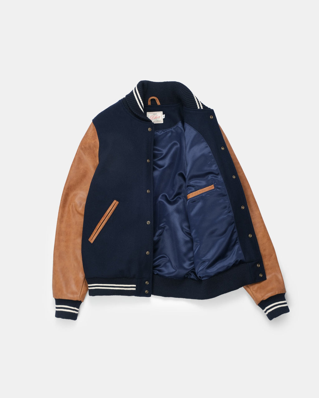 A varsity-style jacket with navy blue knit body, tan faux-suede sleeves, and a navy satin-lined interior, shown flat against a light gray background.
