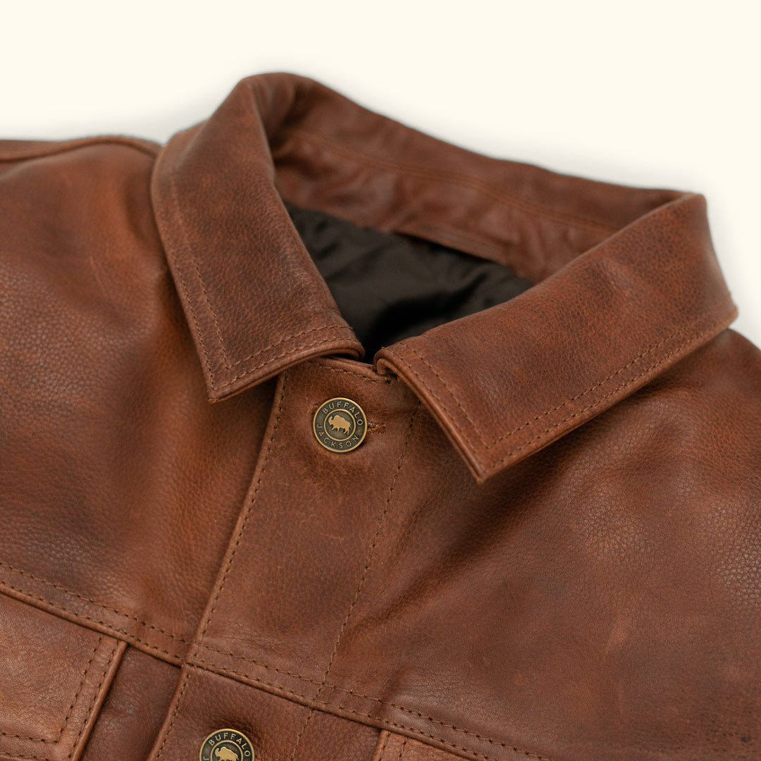 Close-up of a brown leather jacket with a button on a white background