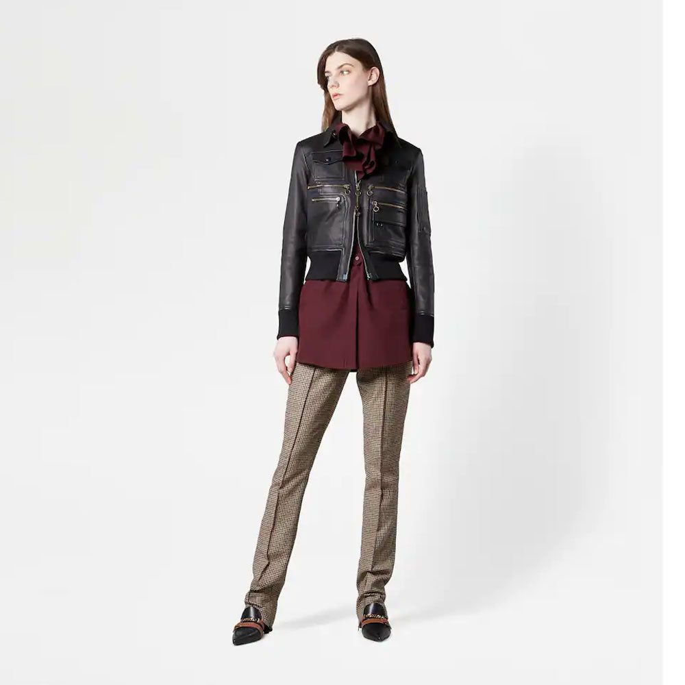 Woman wearing a black leather jacket, burgundy shirt, and patterned pants on a white background