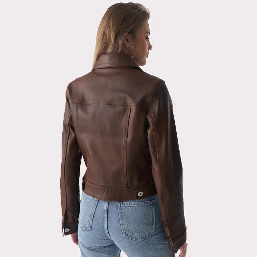 A woman shown from the back wearing a dark brown leather jacket and light blue jeans against a light gray studio background.
