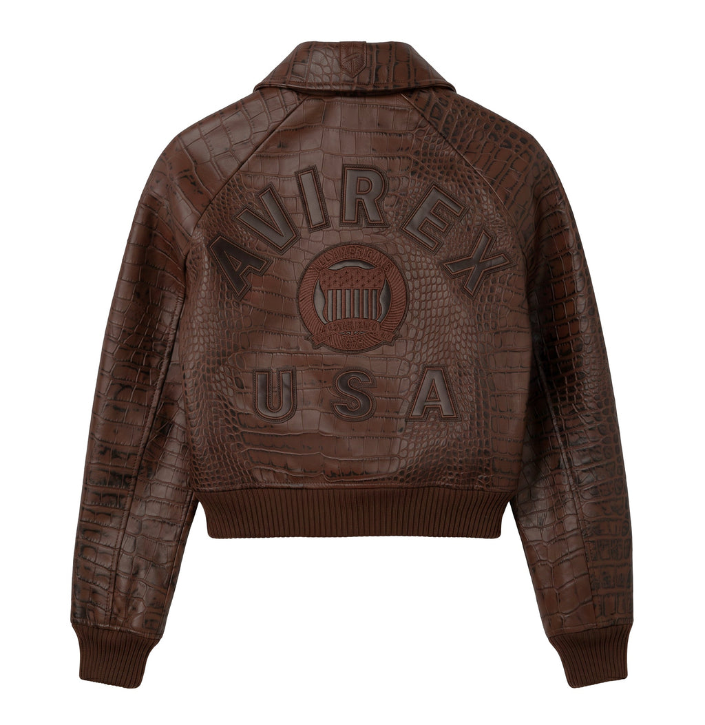 A dark brown cropped bomber jacket with an embossed crocodile pattern, featuring a large debossed 'AVIREX USA' logo on the back.