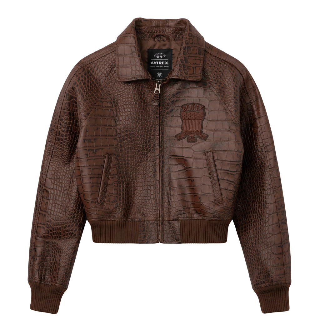 A brown textured leather jacket with crocodile-embossed panels and a tonal embroidered patch on the chest, shown against a plain white background.